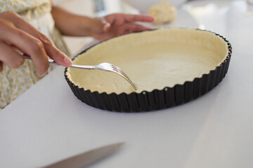 Close up woman baking poking holes into pie crust with fork