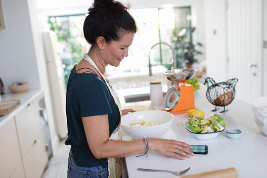 Woman with smart phone baking in kitchen