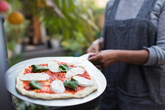 Woman with fresh homemade margherita pizza on peel