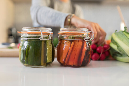 Close up woman pickling vegetables in jars