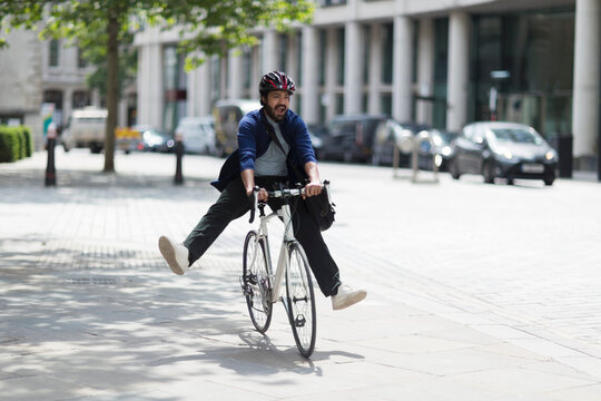 Playful man riding bicycle on sunny city street