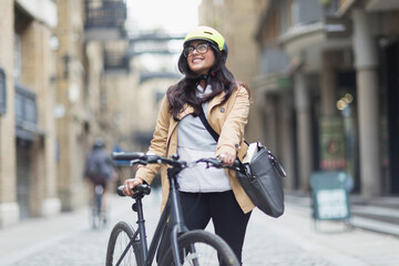 Portrait smiling woman in helmet with bicycle on city street
