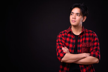 Young handsome Asian hipster man against black background