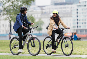 Business people riding bicycles and talking in city park