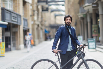 Portrait confident businessman with bicycle in city street