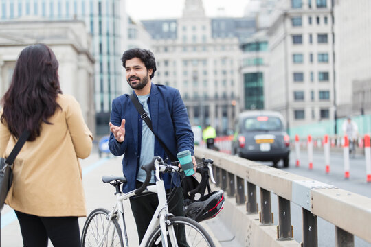 Business people with bicycle talking on urban bridge