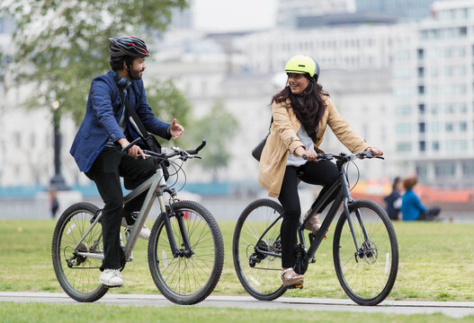 Business People Riding Bicycles And Talking In City Park