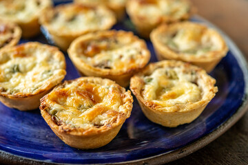 Brazilian gastronomy. Cheese and dried meat pies with arugula in handmade dish on wooden table. © Cacio Murilo