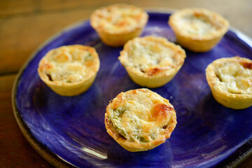 Brazilian gastronomy. Cheese and dried meat pies with arugula in handmade dish on wooden table.