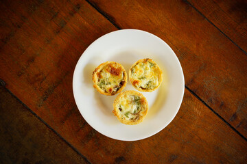 Brazilian gastronomy. Cheese and dried meat pies with arugula in handmade dish on wooden table.