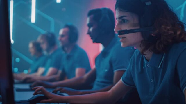 Pro Girl Plays Computer Video Game Talking into Headset with Teammates on a Championship, Brings Victory to a Team and Celebrates. Diverse Cyber Esport Team of Gamers Playing. Side Portrait of People 