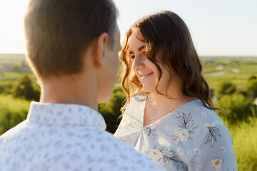 Fototapeta premium Future mum and dad kissing in the park at sunset. High quality photo