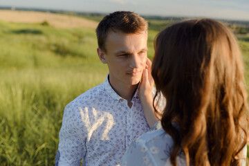 Obraz premium Future mum and dad kissing in the park at sunset. High quality photo