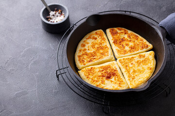 Traditional Scottish tattie potato scones in cast iron pan. Dark background. Copy space.