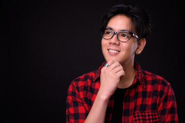Portrait of happy young handsome Asian hipster man with eyeglasses