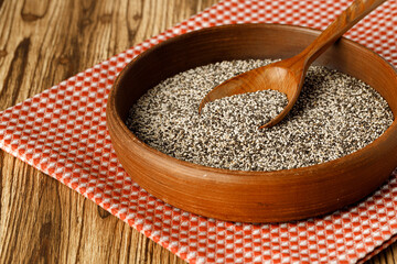 Chia seeds in a bowl with wooden spoon