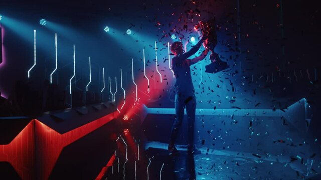 eSports Winner Trophy Standing on a Stage in the Middle of the Computer Video Games Championship Arena. Two Rows of PC for Competing Teams. Stylish Neon Lights with Cool Area Design. Dolly Shot