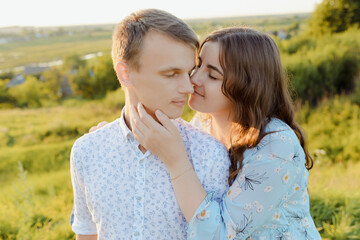Fototapeta premium Pregnant woman is kissing with her husband at sunset. Happy family