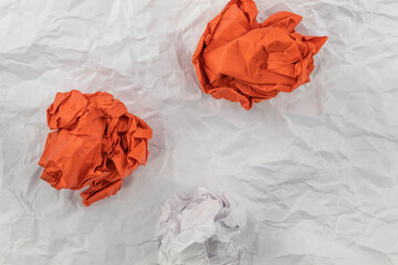 Two red crumpled papers and one white paper lie on a white paper background