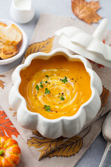 Pumpkin and carrot cream soup in bowl. Grey background. Close up.