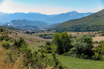 Fototapeta na wymiar Large valley with farms, plantations, forest and mountains in the background, Monteleone di Spoleto, Umbria region, Perugia province, Italy