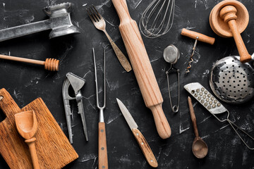 Various kitchen utensils and tools on a black stone background. Top view, flat lay, copy space....