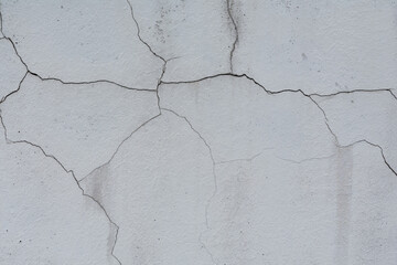 Texture of a gray wall covered with plaster that has burst with time