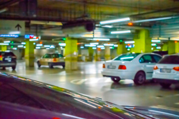 Fototapeta na wymiar Parking lot cars blurred. Car lot parking space in underground city garage. Empty road asphalt background in soft focus. Industrial Shed or Parking Lot.