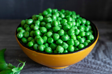 Fresh green peas in cup on wooden background. Rustic table background.