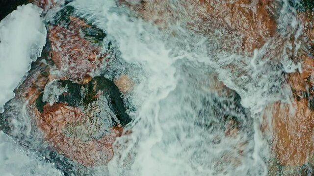 river with ice and foam in the winter, a log in the water, icicles on the rocks