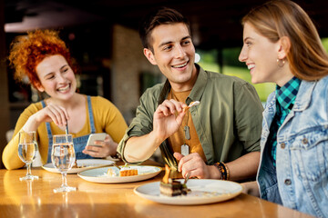 Happy man sharing his dessert with female friend in a cafe.
