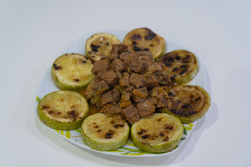 Plate with stews and zucchini on white background