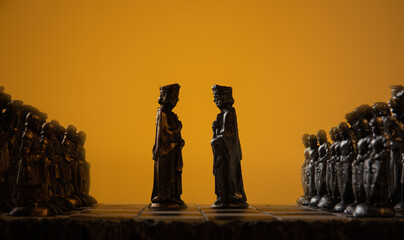stylized chess pieces on a board with orange background and selective focus