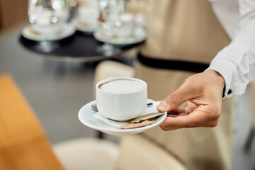 Close-up of a waiter serving coffee in a cafe.