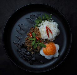 Thai food stir-fried minced pork spicy and basil with rice and fried egg and black plate top view 