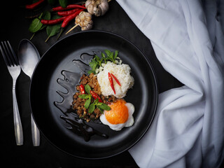 Thai food stir-fried minced pork spicy and basil with rice and fried egg and black plate top view 