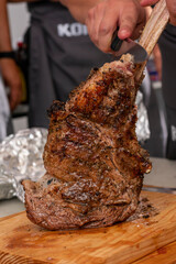 manos preparando distintos cortes en el asador y parrilla. tomahwk , rib eye , new york  tuetatons  con sal y mienta 
