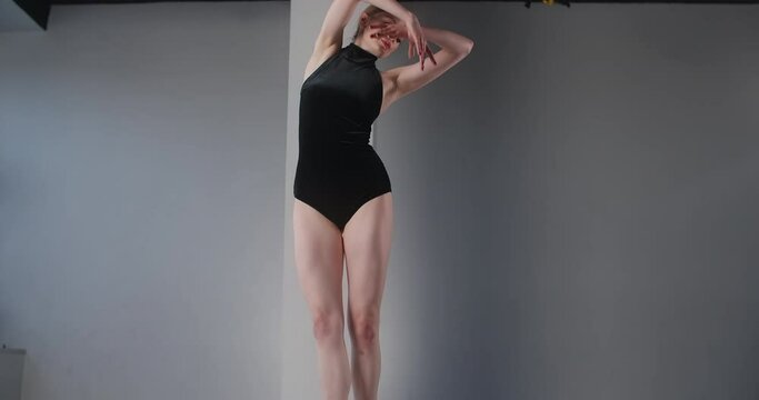 Pretty young ballerina in black stage costume with open back rehearses dance moves, ballet rehearsal, dancing in pointe shoes on the tiptoes, dance studio lesson, 4k 60p Prores HQ 10 bit
