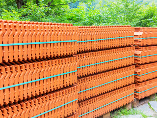 Red roof tiles are packed in standard packaging on building pallets for further transport.