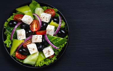 Vegetable salad with fresh cucumber, tomato, olive, onion, lettuce and feta cheese. Healthy food. Top view. Copy space