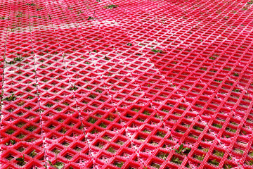 Background red plastic road grid with sprouted green grass