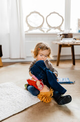 Toddler girl dressing doll in living room