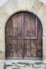 Fototapeta na wymiar Heavy wooden door. Ancient gate on the facade of a stone building. The architecture of medieval Spain. Streets of Pamplona. Catholic Church. Massive door with a lock.