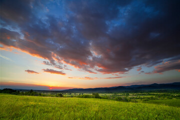 Obraz premium Dramatic sunset over green field