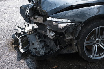 Car crash collision in urban street. Front of black color car big damaged and broken. Concept - End Of The Road. 