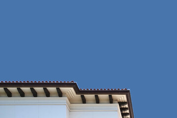 Fototapeta na wymiar Low angle view of the edge of a large building in the southern California modern Spanish heritage style under blue sky