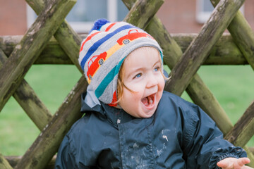 Laughing toddler girl in front of wooden fence