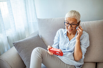 Senior woman talking on the phone and holding a pack of pills.  Woman refilling her medication...