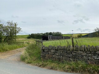 Obraz premium Old farm outbuildings, within dry stone walls, and an open gate, high on the hills above, Sowerby Bridge, Yorkshire, UK