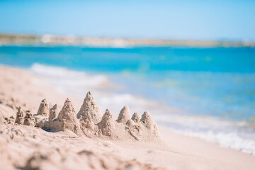 Sandcastle at white tropical beach with plastic kids toys